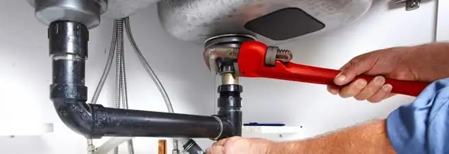 Garbage disposal repair technician tightening the sink drain and disposal connection in Providence, RI