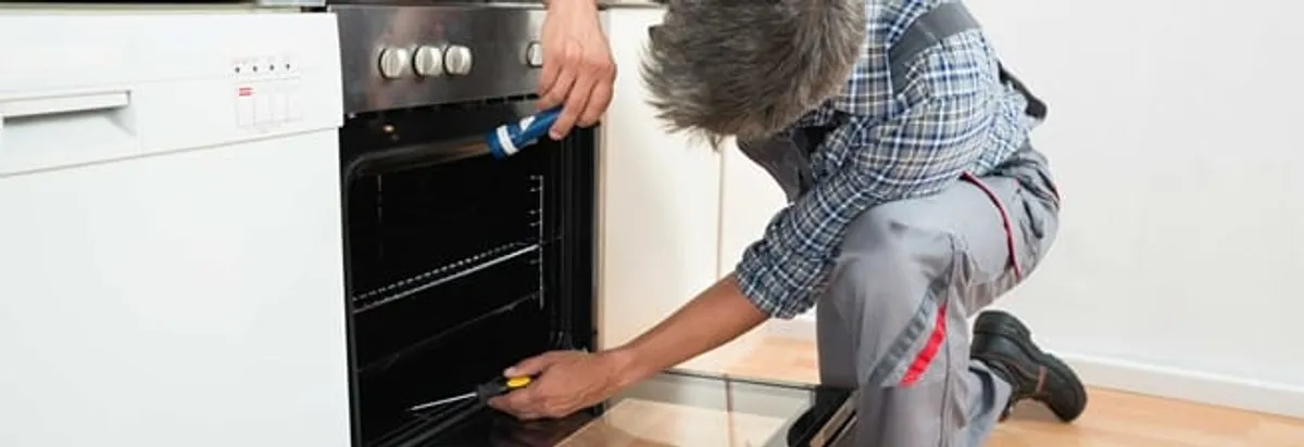 Oven repair technician inspecting and servicing an electric oven in Providence, RI