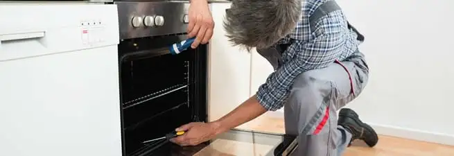 Oven repair technician inspecting and servicing an electric oven in Providence, RI