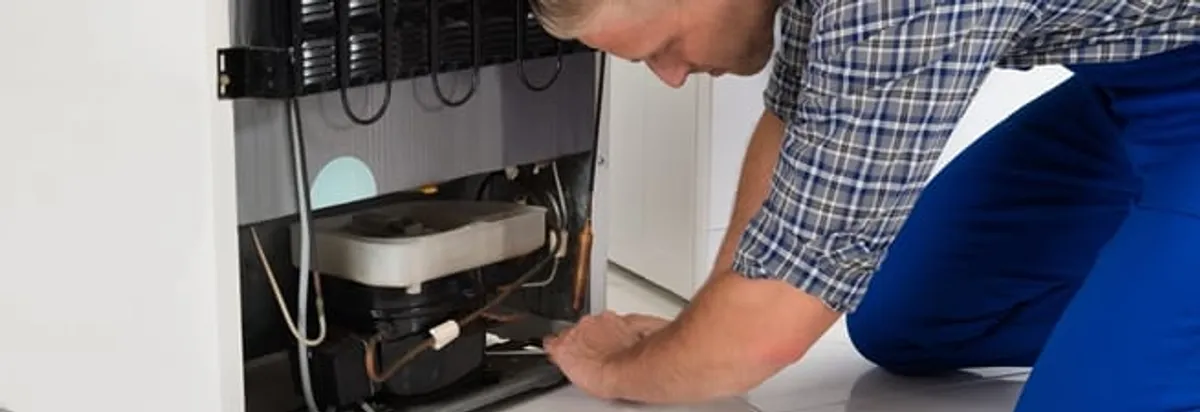 Refrigerator repair technician servicing the compressor and condenser area in Providence, RI