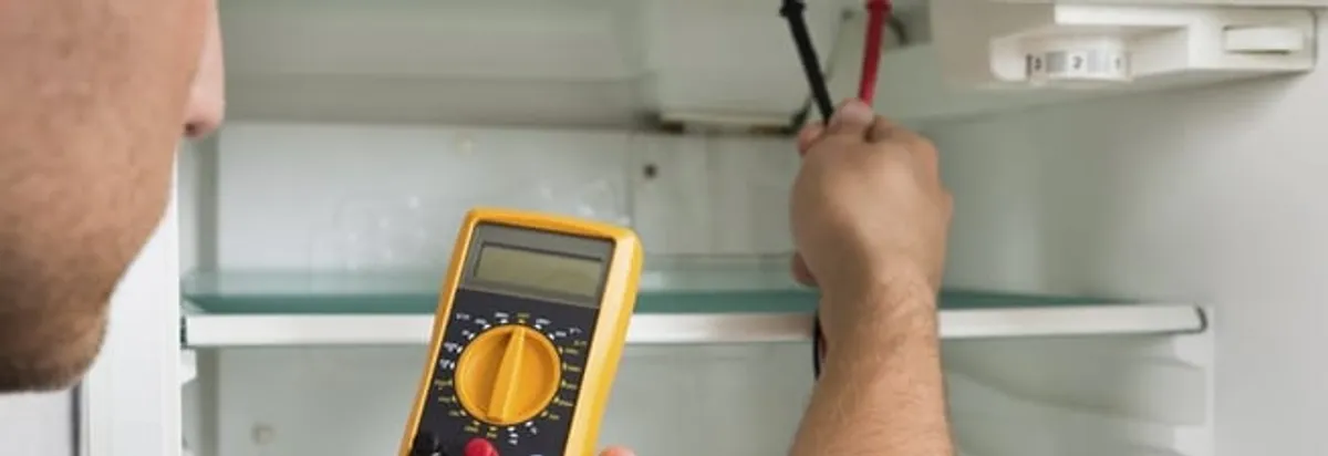 Refrigerator repair technician testing electrical components with a multimeter in Providence, RI