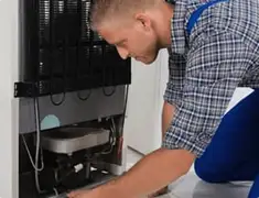Refrigerator repair technician servicing the compressor and condenser area in Providence, RI