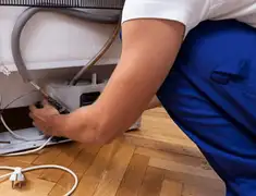 Appliance repair technician fixing refrigerator water line and connections in Providence, RI