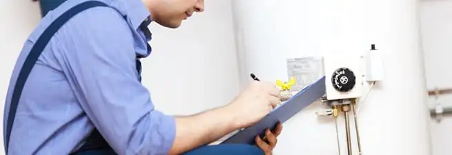Water heater repair technician inspecting the unit and recording service notes in Providence, RI