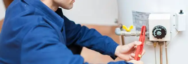 Water heater repair technician adjusting the temperature control and gas valve in Providence, RI